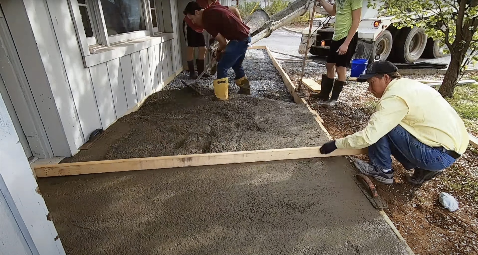 Professional concrete team smoothing and leveling fresh concrete slab installation for residential driveway project